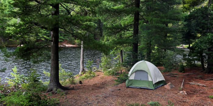 A tent out in the woods by water