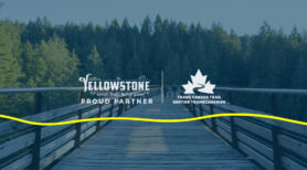 Yellowstone Bourbon and Trans Canada Trail Logos over an image of a wooded trail with a boardwalk running through it.
