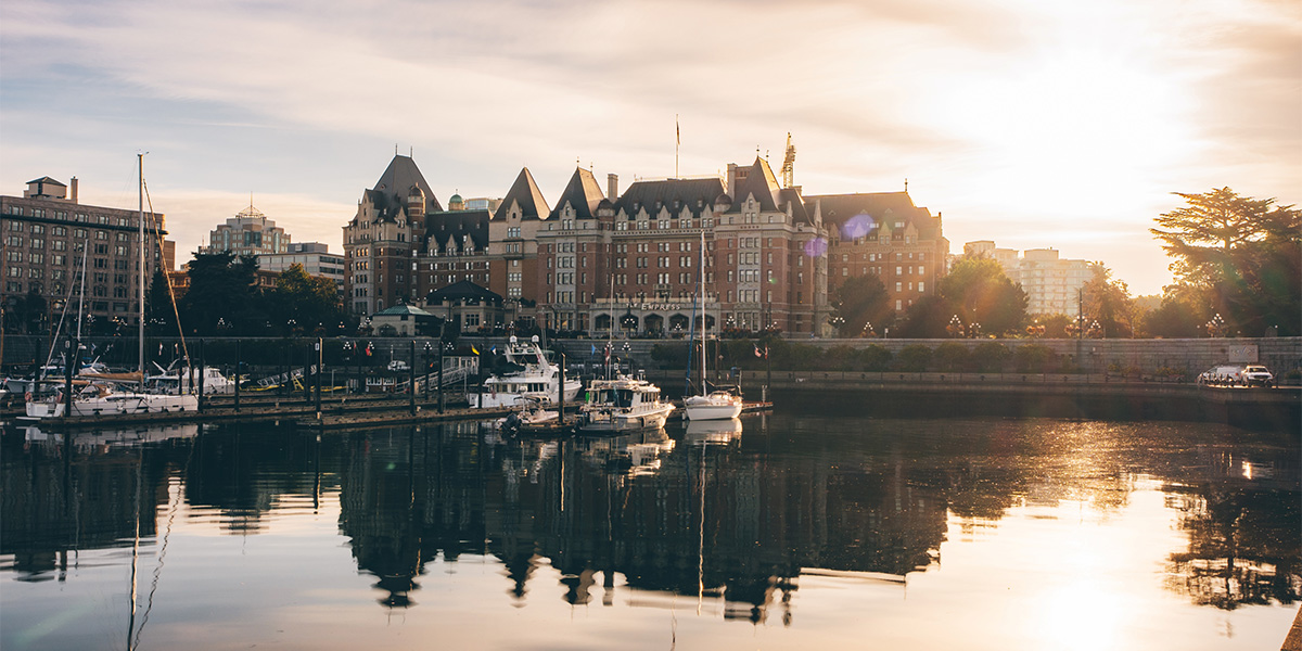 The Fairmount Express Hotel in Victoria, BC, basking in sunlight, showcasing its grand architecture against a clear sky. L'hôtel Fairmount Express de Victoria, en Colombie-Britannique, baigné de soleil, mettant en valeur sa grande architecture dans un ciel dégagé.