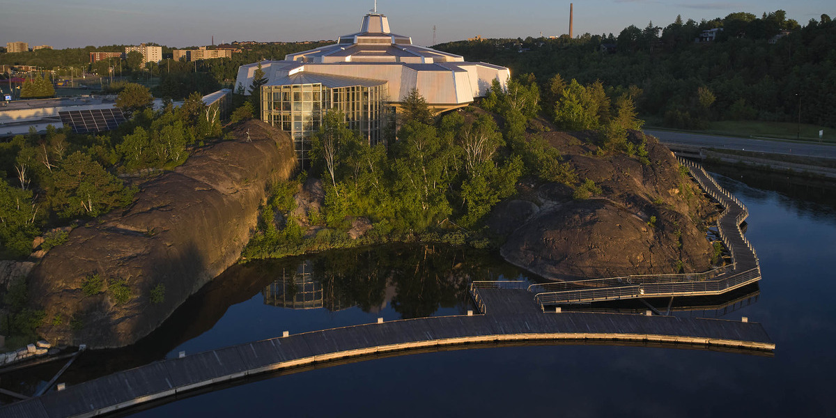 00Feature_ON_Bell Park Walkway story_credit Science North | Trans Canada Trail large building atop a hill with trees birdeye