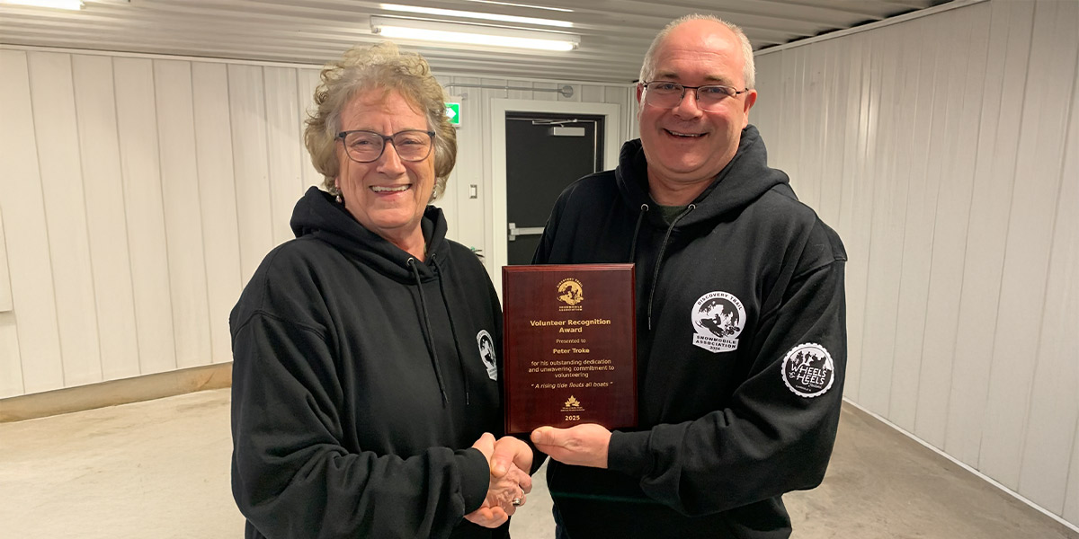 00Feature image_Peter Troke volunteer recognition piece_credit Discovery Trail Snowmobile Association | Trans Canada Trail man and woman smiling shaking hands holding award plaque