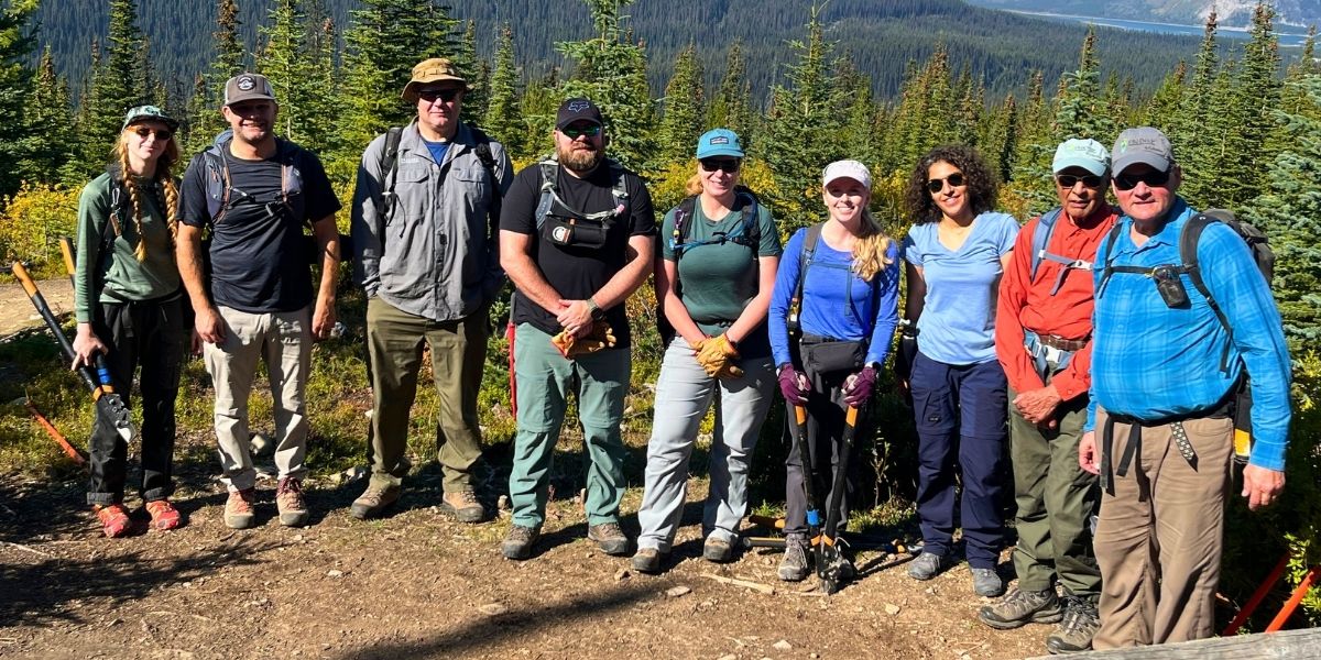group of people in hiking gear standing on mountain on a sunny day