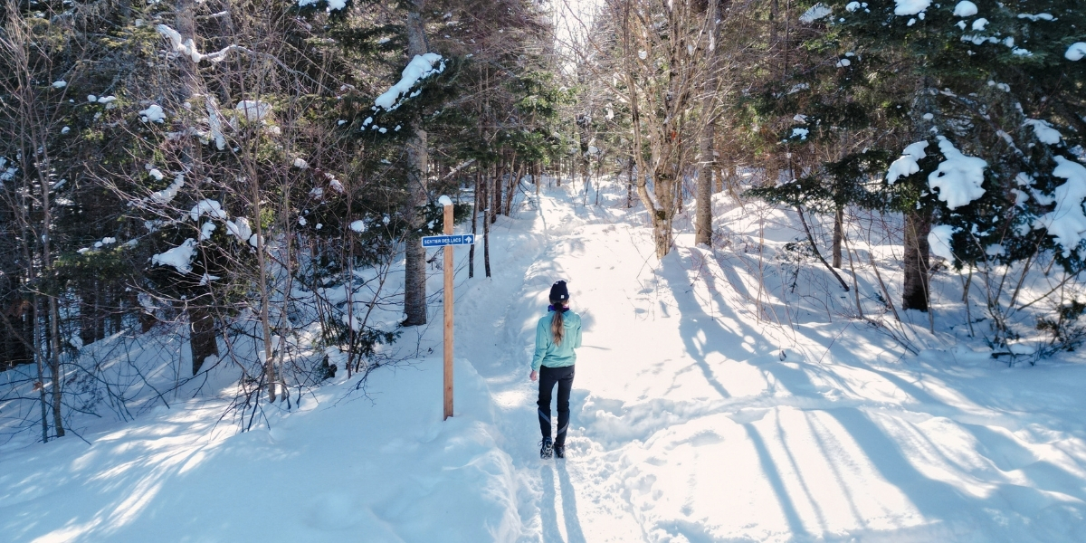 woman walking on snowy trail on sunny day