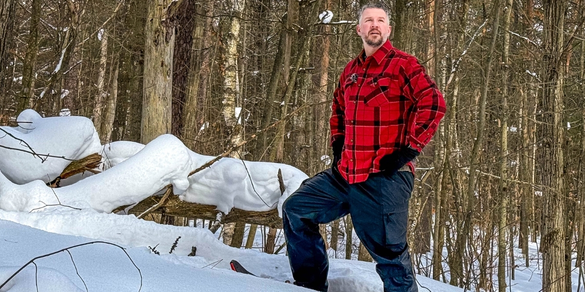 man standing on snowshoes posing on a snowy day in forest