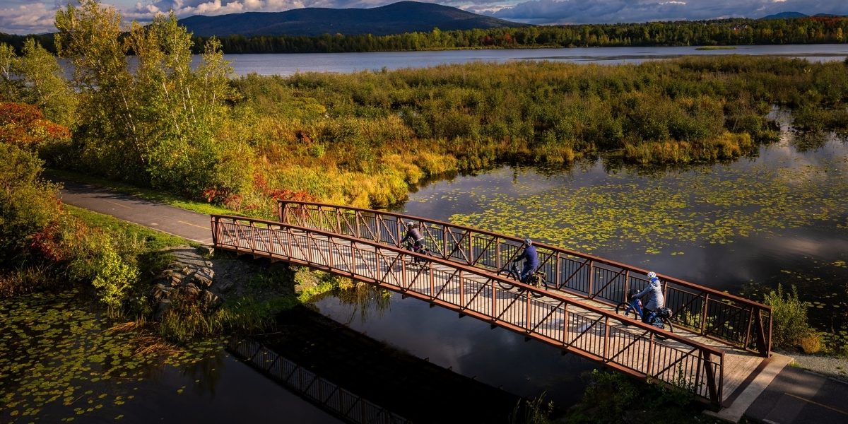 00Feature image_Véloroute gourmande_no credit required | Trans Canada Trail birdseye of a bridge over a marsh with greenery and rolling hills behind