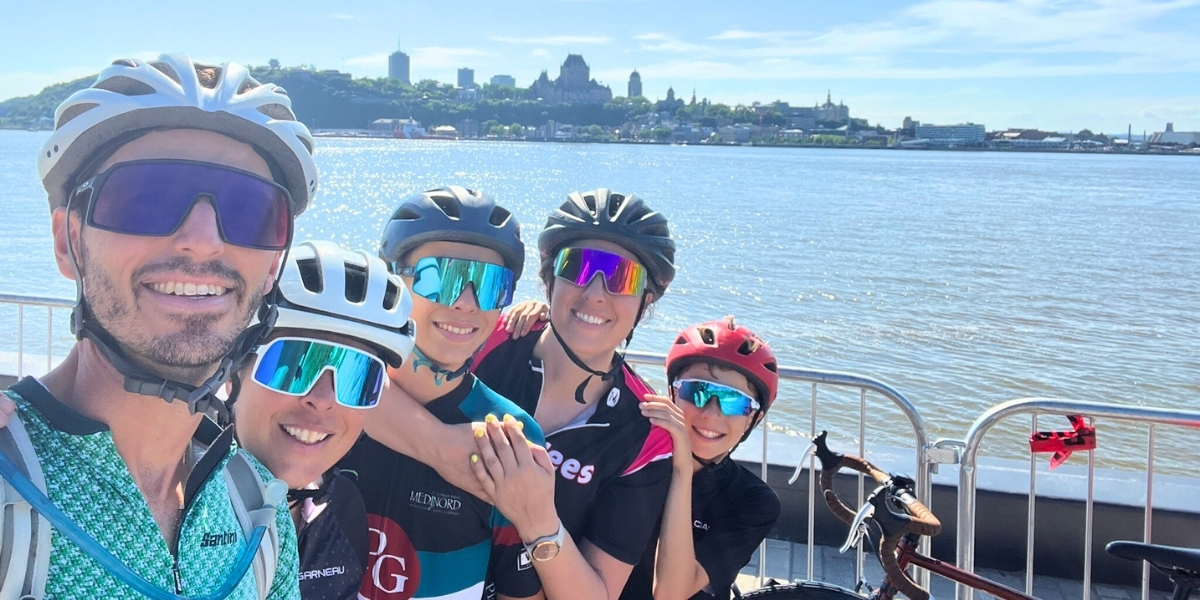 00Feature image_Web story_Pat Lee_credit Alex Genest | Trans Canada Trail group family selfie in biking gear infront of water and skyline