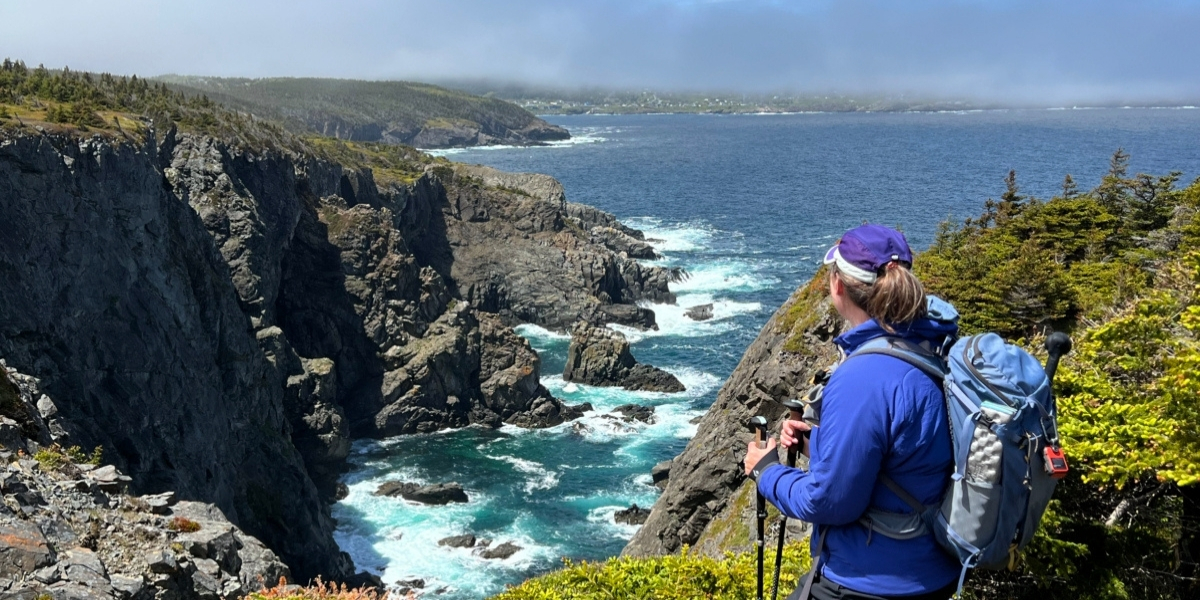 00Feature image_NL_Taryn Eyton East Coast Trail_credit Taryn Eyton | Trans Canada Trail A person looking out over a rocky cliff with the ocean below