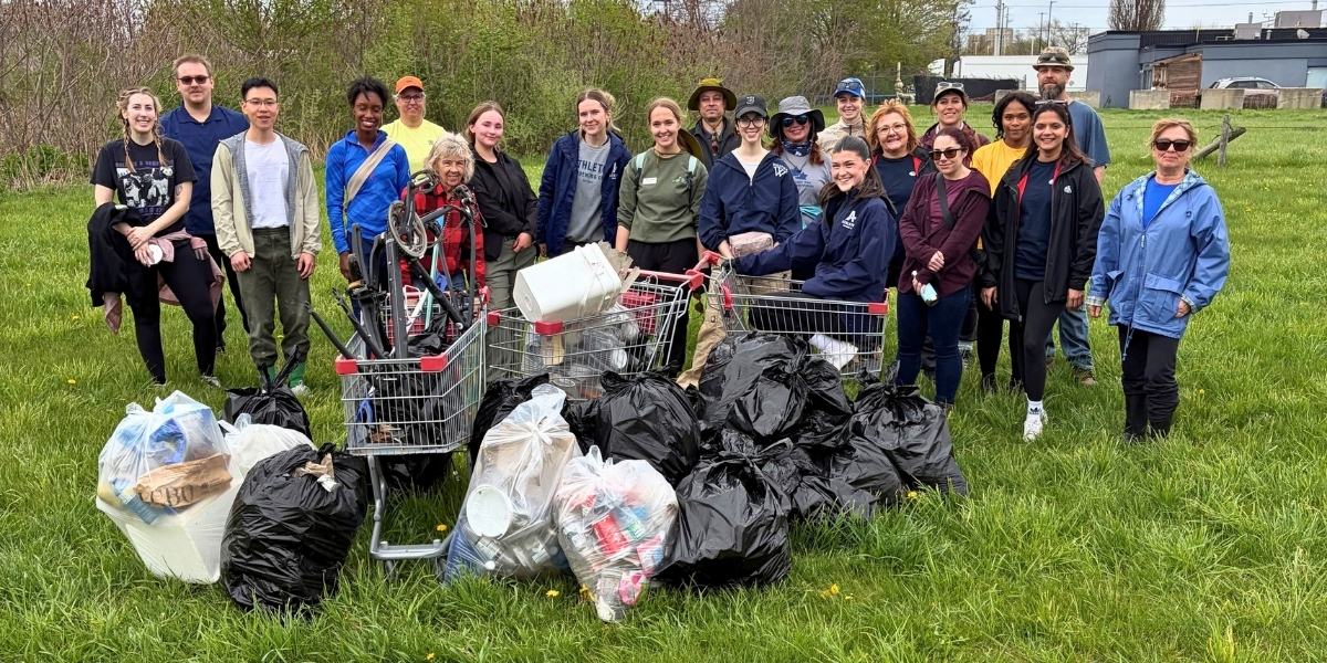 00Feature image_TC Energy story_Trail clean up wit the Hamilton Conservation Foundation_credit Hamilton Conservation Foundation Griffin Moore | Trans Canada Trail Diverse volunteers pose in a field behind bags of trash and carts filled with litter from a cleanup.